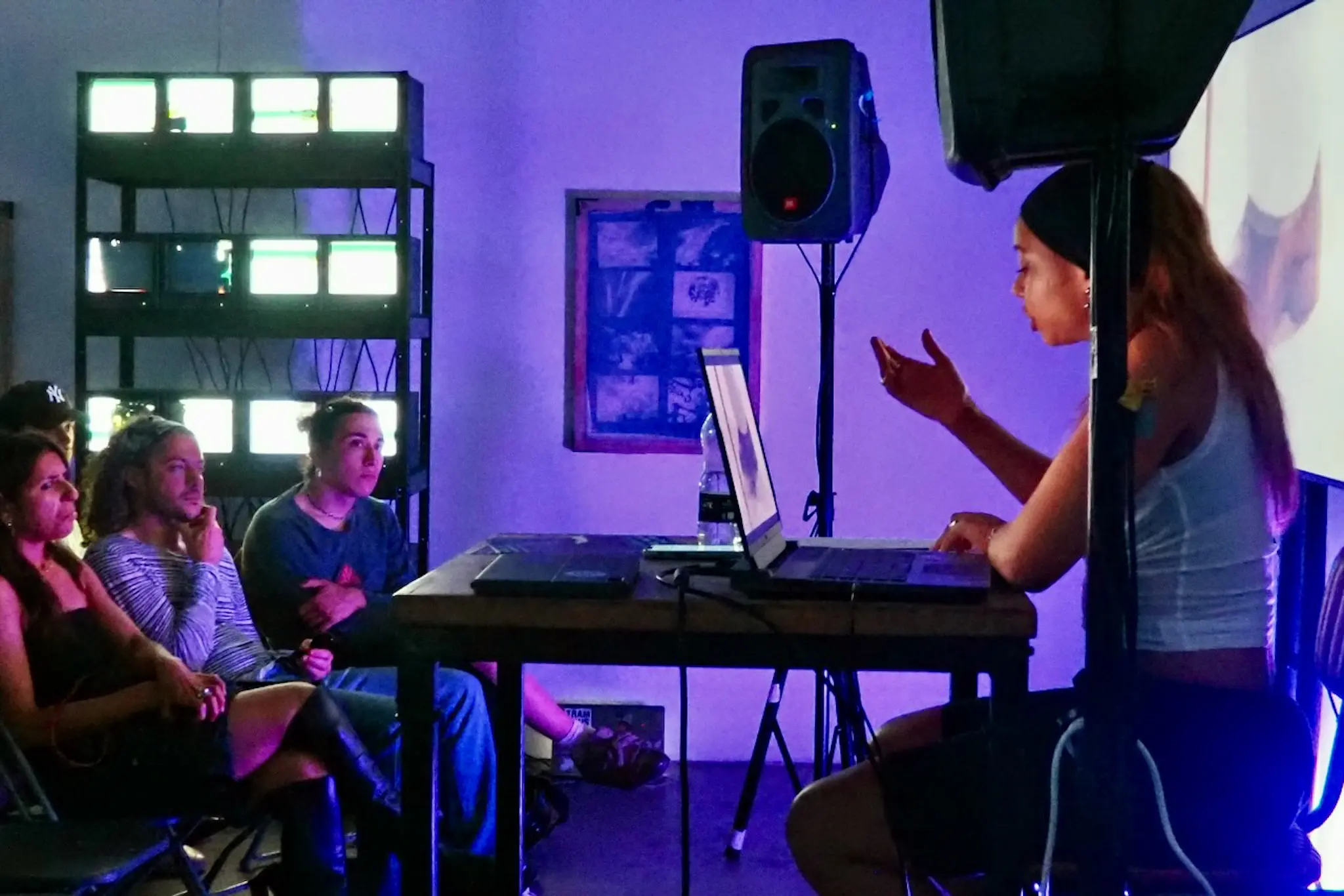 Purple-lit room with audience and projection screen at Dian Joy’s talk