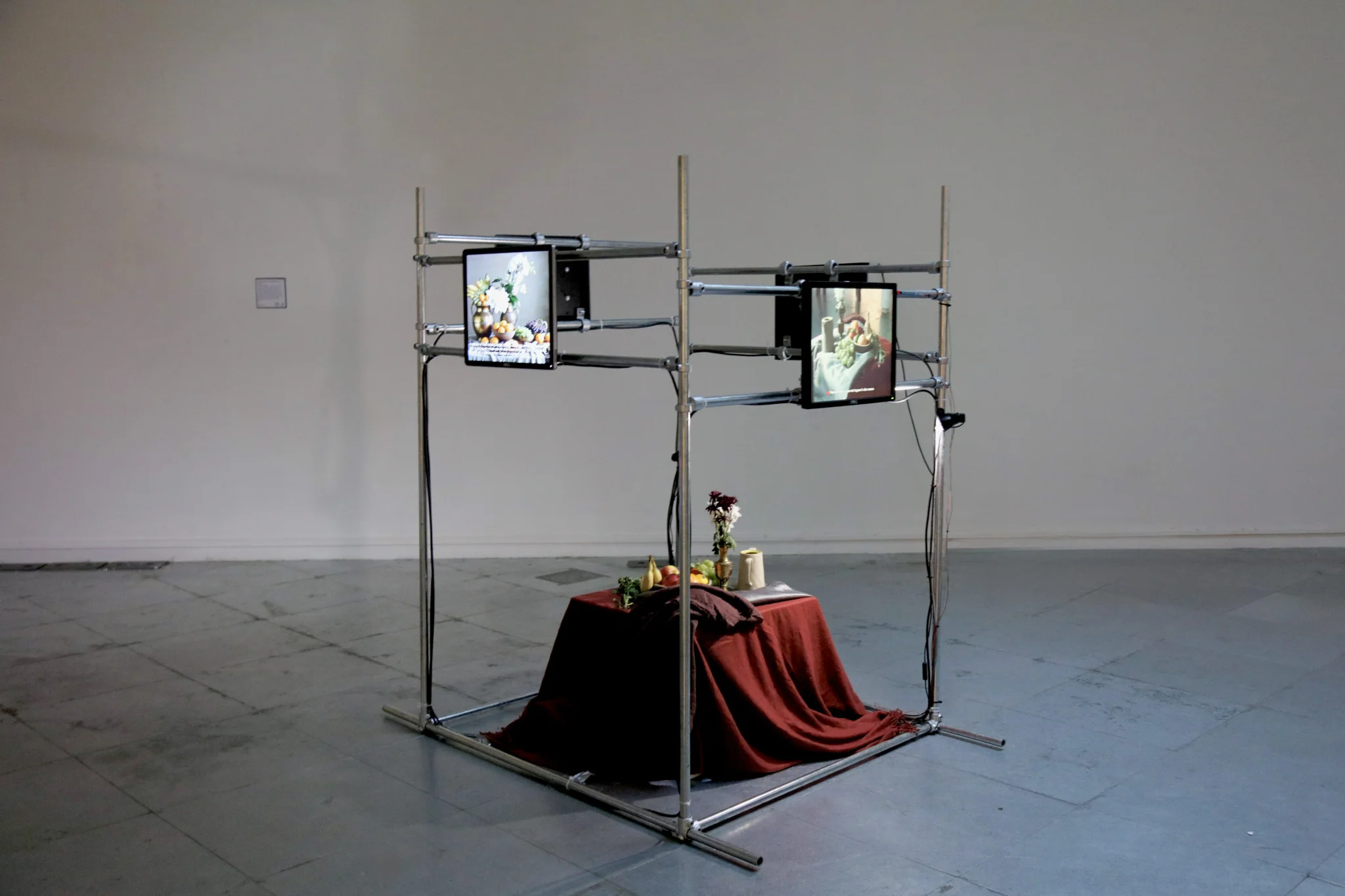 A screen held with metal bars, showing a still life scene of fruit in the centre